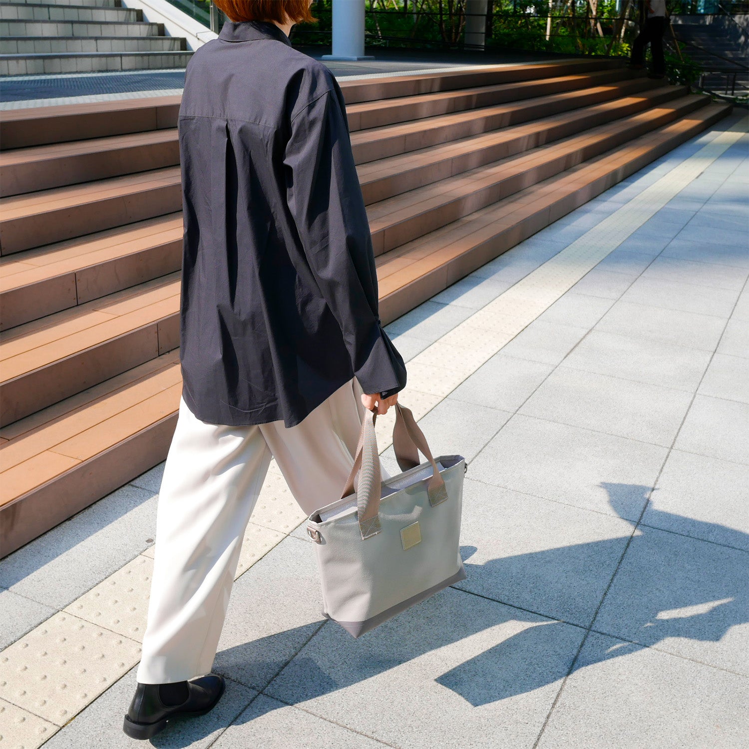 女性モデルが身長165cm【KEVIN】グレー色を持った全身コーディネート写真。バッグのサイズ感が一目で分かる