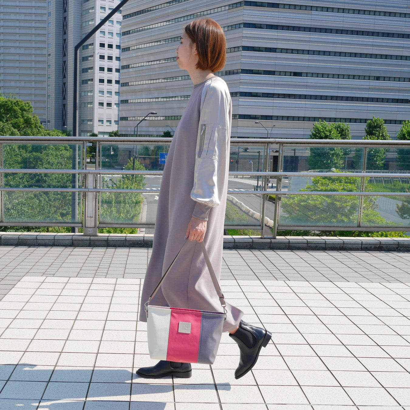 ホワイト、レッド、グレーの切り返し身長165cmのモデルがショルダーバッグをワンショルで着用。付属ナイロンベルト（幅3.8cm、長さ75〜135cm）を使用した着用イメージ。