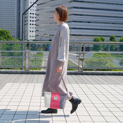 ホワイト、レッド、グレーの切り返し身長165cmのモデルがショルダーバッグをワンショルで着用。付属ナイロンベルト（幅3.8cm、長さ75〜135cm）を使用した着用イメージ。