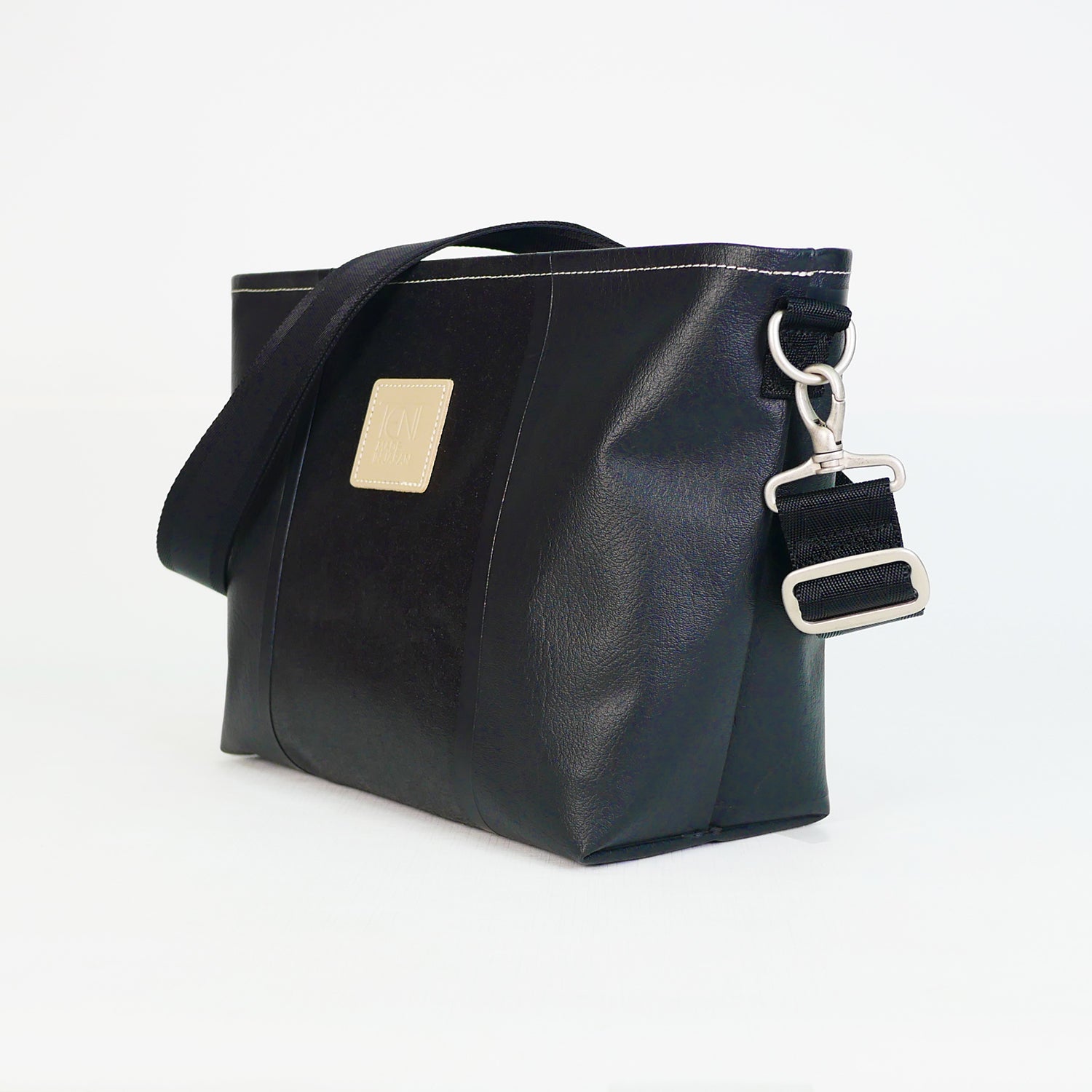 ブラックのPVCコーティングポリエステル製2WAYショルダーバッグ斜め全体像。付属ナイロンベルト幅3.8cm、長さ75〜135cmで調整可能。