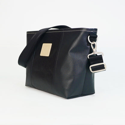 ブラックのPVCコーティングポリエステル製2WAYショルダーバッグ斜め全体像。付属ナイロンベルト幅3.8cm、長さ75〜135cmで調整可能。