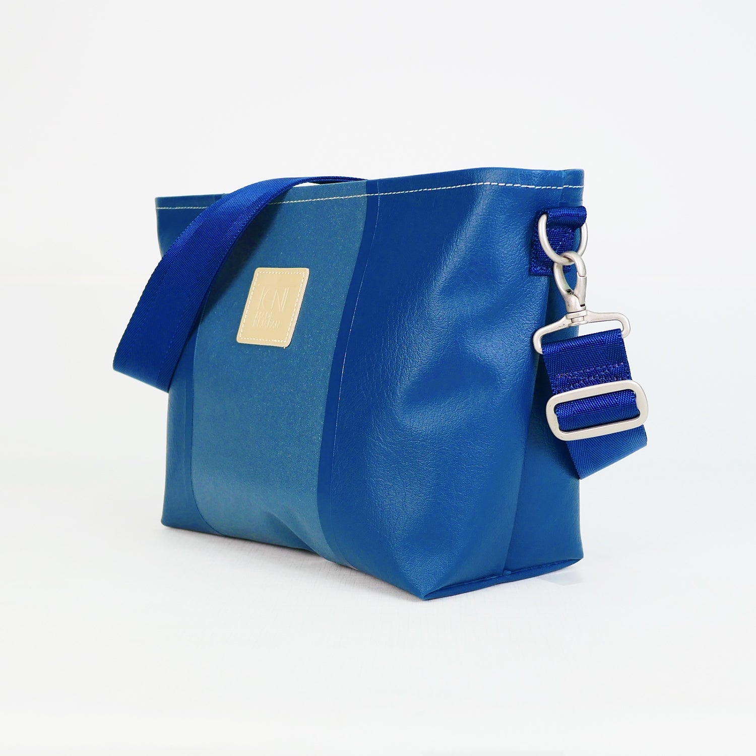 ネイビーのPVCコーティングポリエステル製2WAYショルダーバッグ斜め全体像。付属ナイロンベルト幅3.8cm、長さ75〜135cmで調整可能。