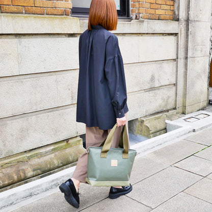 女性モデル身長165cmが【KEVIN】カーキ色を持った全身コーディネート写真。バッグのサイズ感が一目で分かる