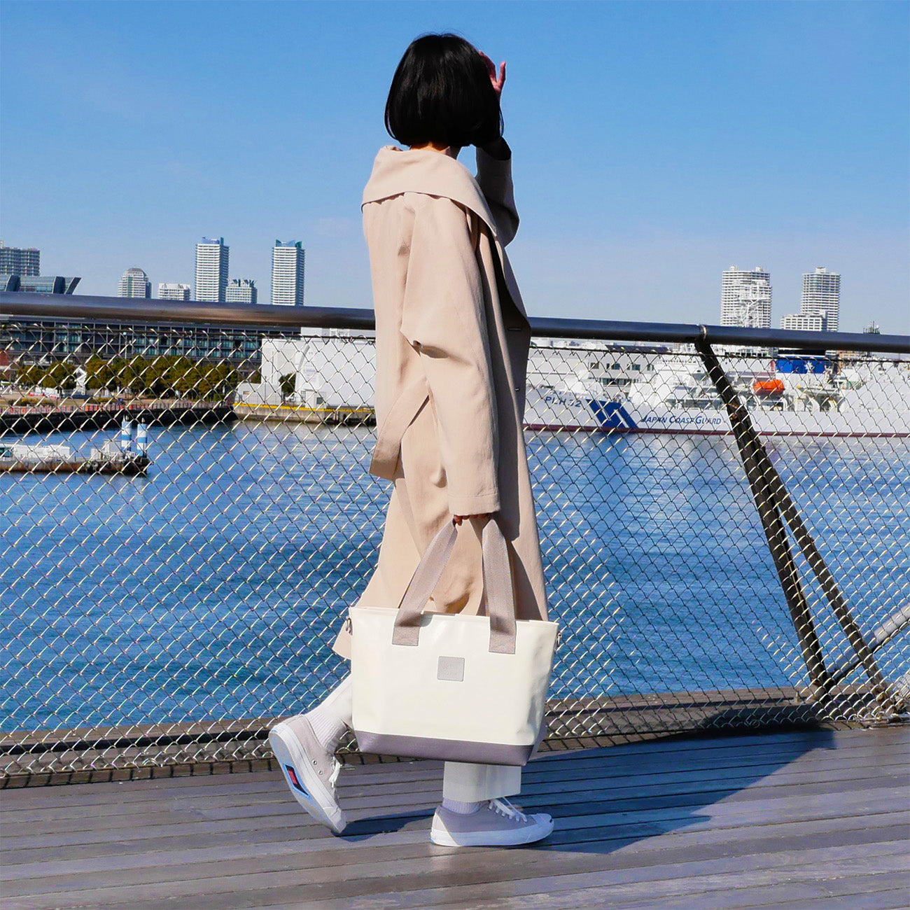 女性モデル身長165cmが【KEVIN】アイボリーを持った全身コーディネート写真。バッグのサイズ感が一目で分かる