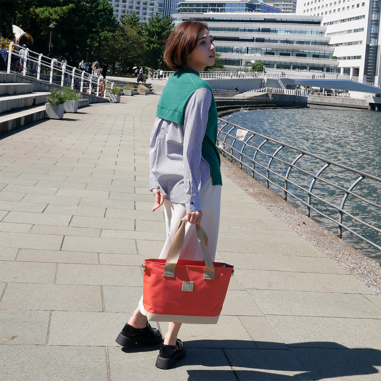 女性モデル身長167cmが【KEVIN】オレンジ色を手に持った写真。バッグの高さ28.5cmのバランスが伝わる構図