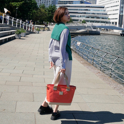 女性モデル身長167cmが【KEVIN】オレンジ色を手に持った写真。バッグの高さ28.5cmのバランスが伝わる構図